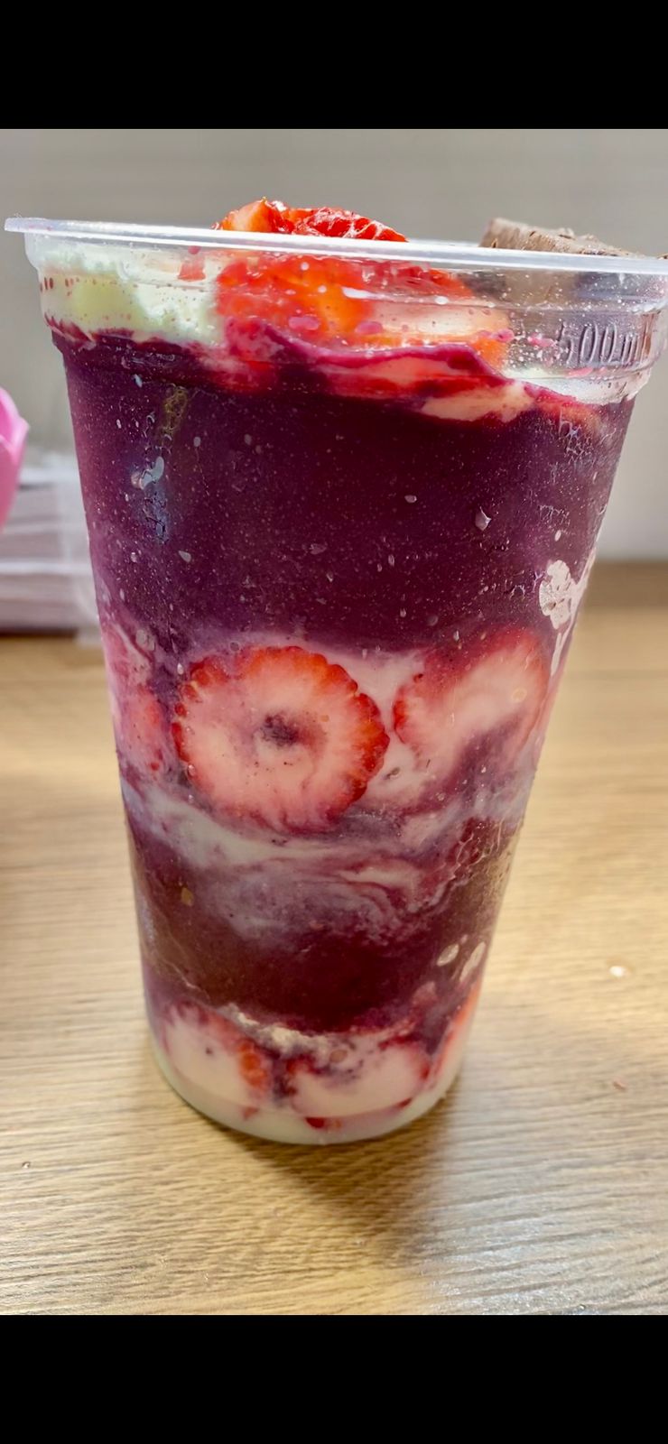 Close de copo de açaí com morango e creme